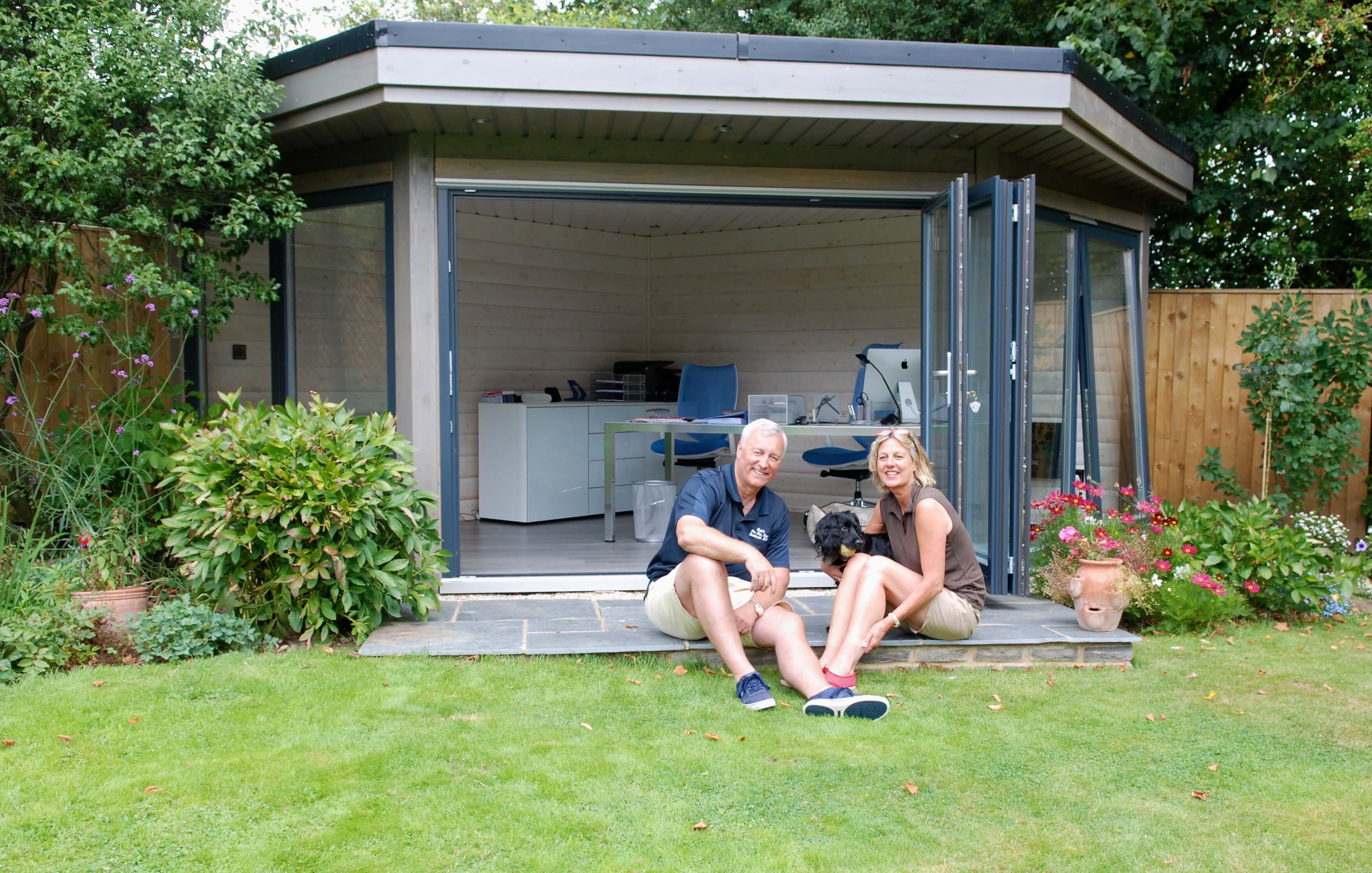 The Boyds relaxing next to their solid log garden office